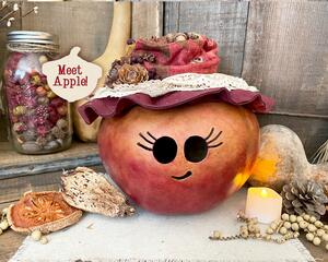 This is a fall apple decoration. It is a real gourd with a happy face  carved into it. This gourd is named Apple and has a lacy handmade hat